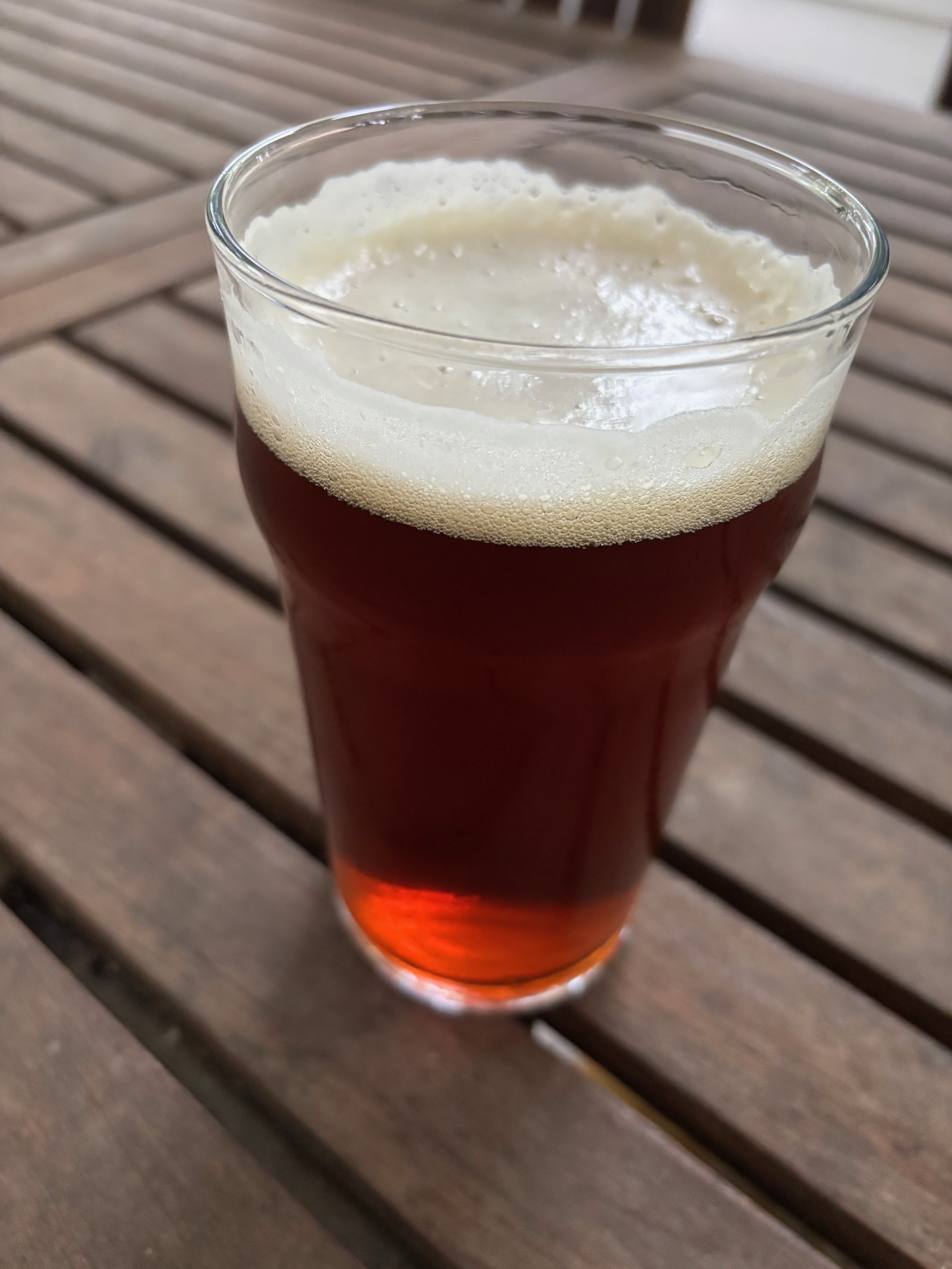 Dark Mild ale in a nonic glass on a wooden table