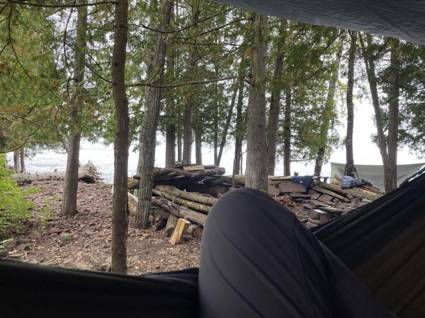 View from my hammock with an elaborate firepit and trees in the middle ground and Lake Superior in the background
