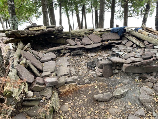 An elaborate firepit with improvised seating made from large stones with a nook for storing firewood