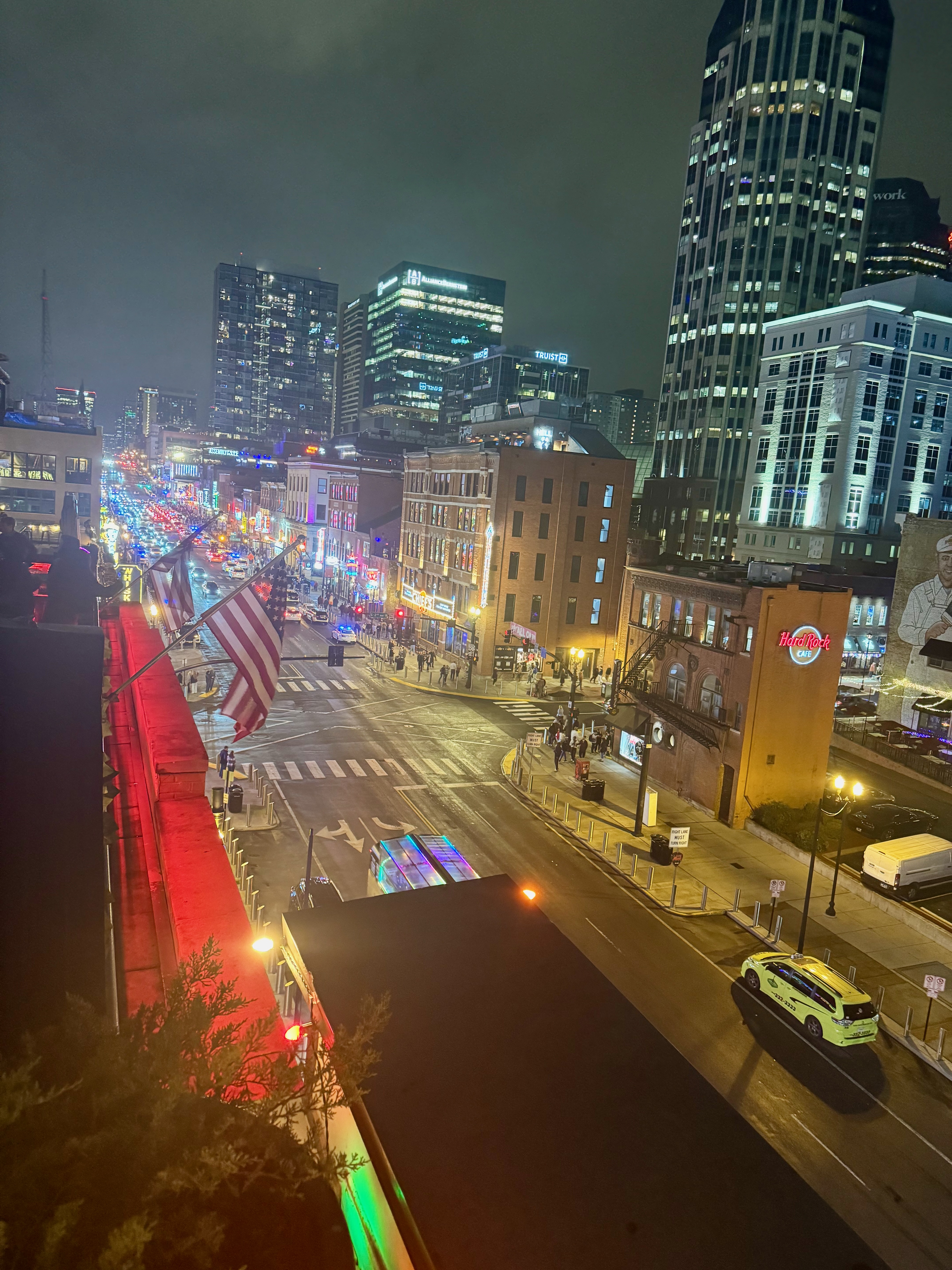 View from the roof of Acme Feed & Seed down Broadway at night—street full of traffic and sidewalks full of people going between bars, each adorned with a bright neon sign