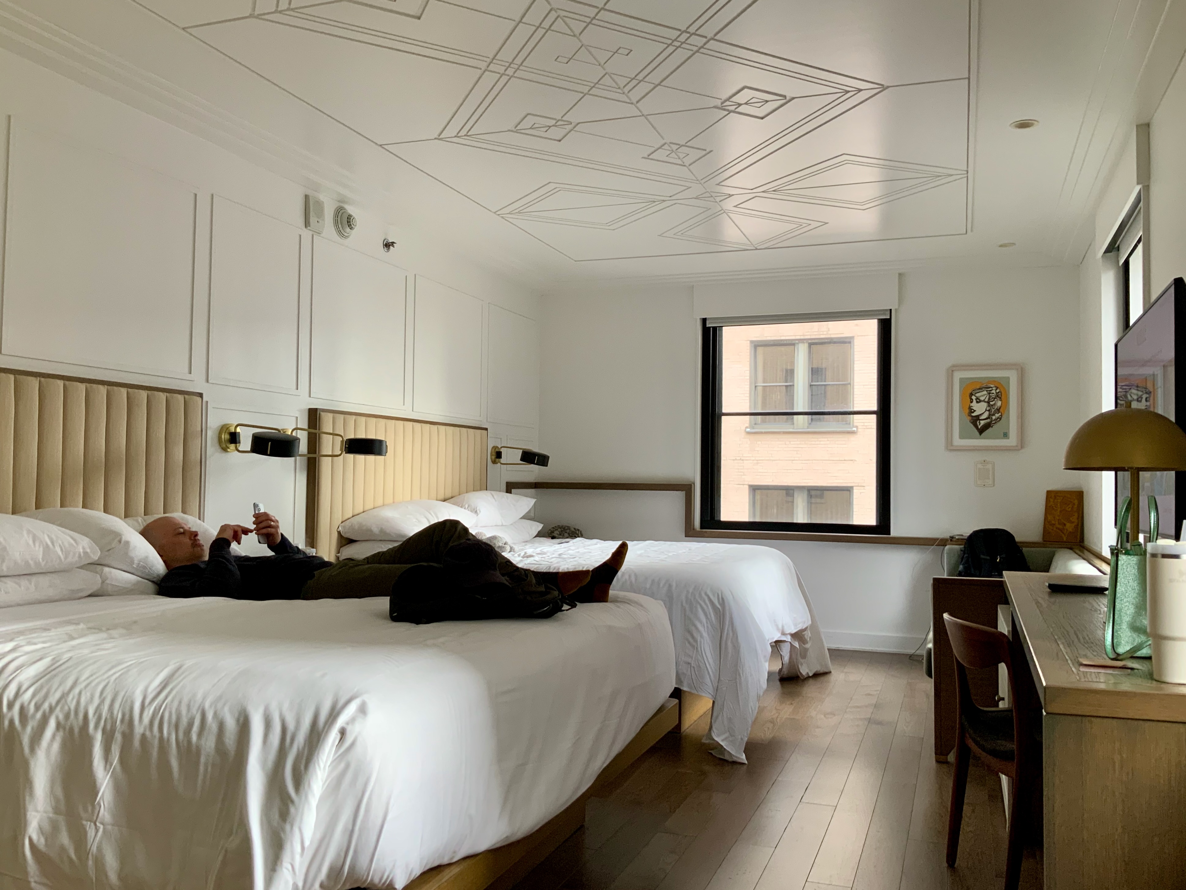 The author, lying on a hotel room bed, browsing his phone