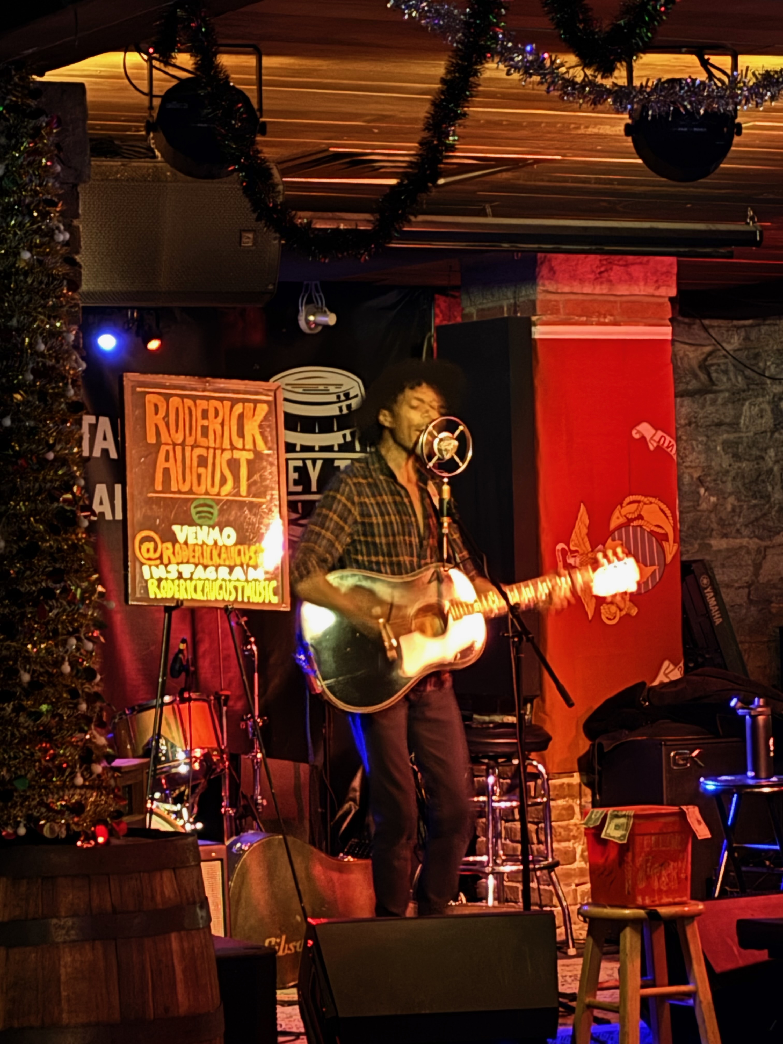 Roderick August singing and playing guitar on stage