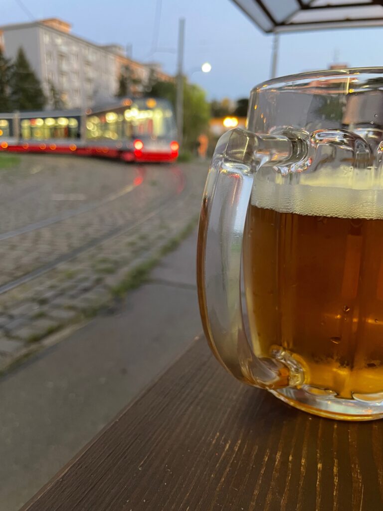 Half liter glass mug of Pilsner Urquell with tram in background