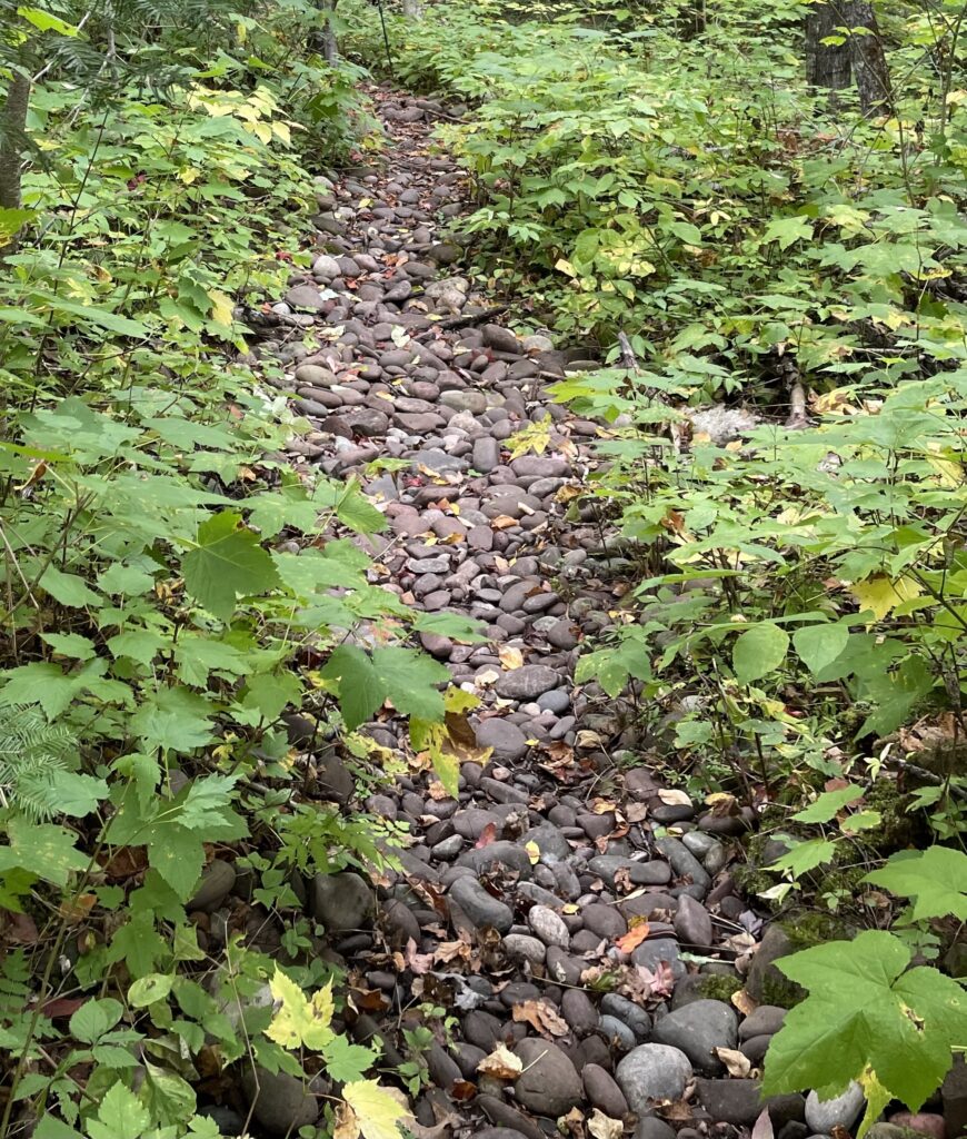 Hiking trail covered with smooth, moderately sized stones of shale, granite, and basalt